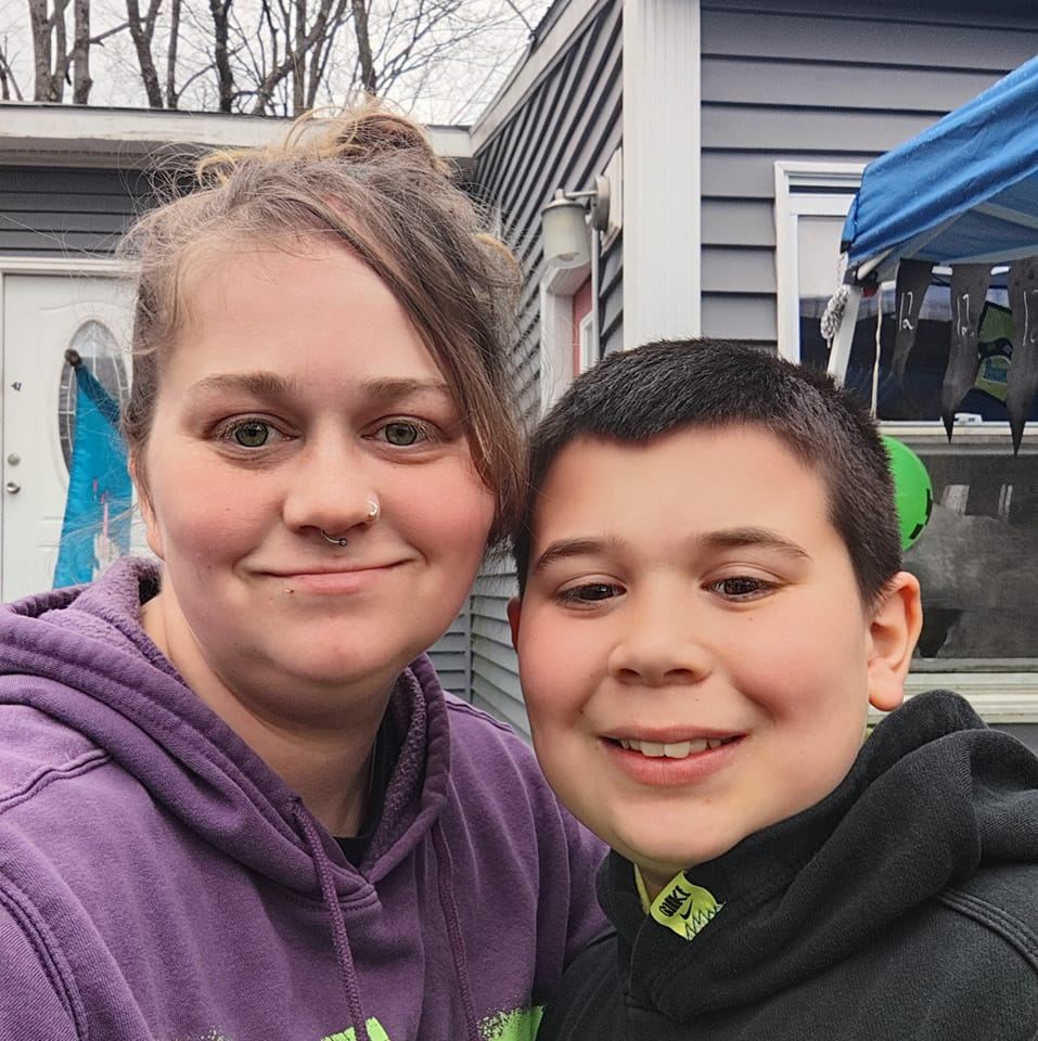 A mom with a nose ring wearing a purple hoodie, with her type 1 diabetic son, smiling at the camera.