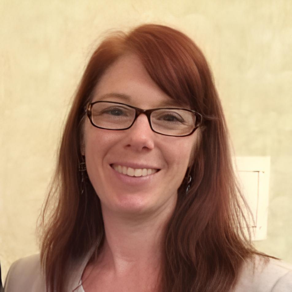 Wendy Hermes smiling, wearing black rim glasses and red hair.