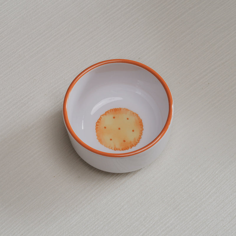 Slightly angled looking down on the crackers Macro Bowl, showing a colorful illustration of a golden round cracker on the bottom of the bowl.