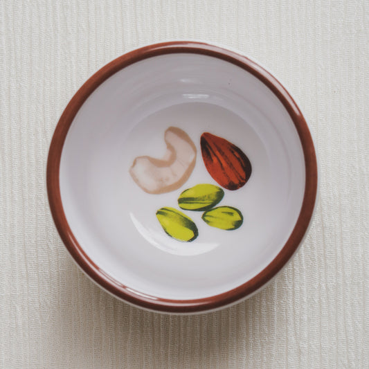 Looking down on the nuts bowl, showing a colorful illustration at the bottom of the bowl of pistachios, cashews, and almonds.