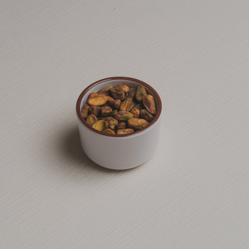 A slightly angled down view of the nuts Macro Bowl filled with pistachios.