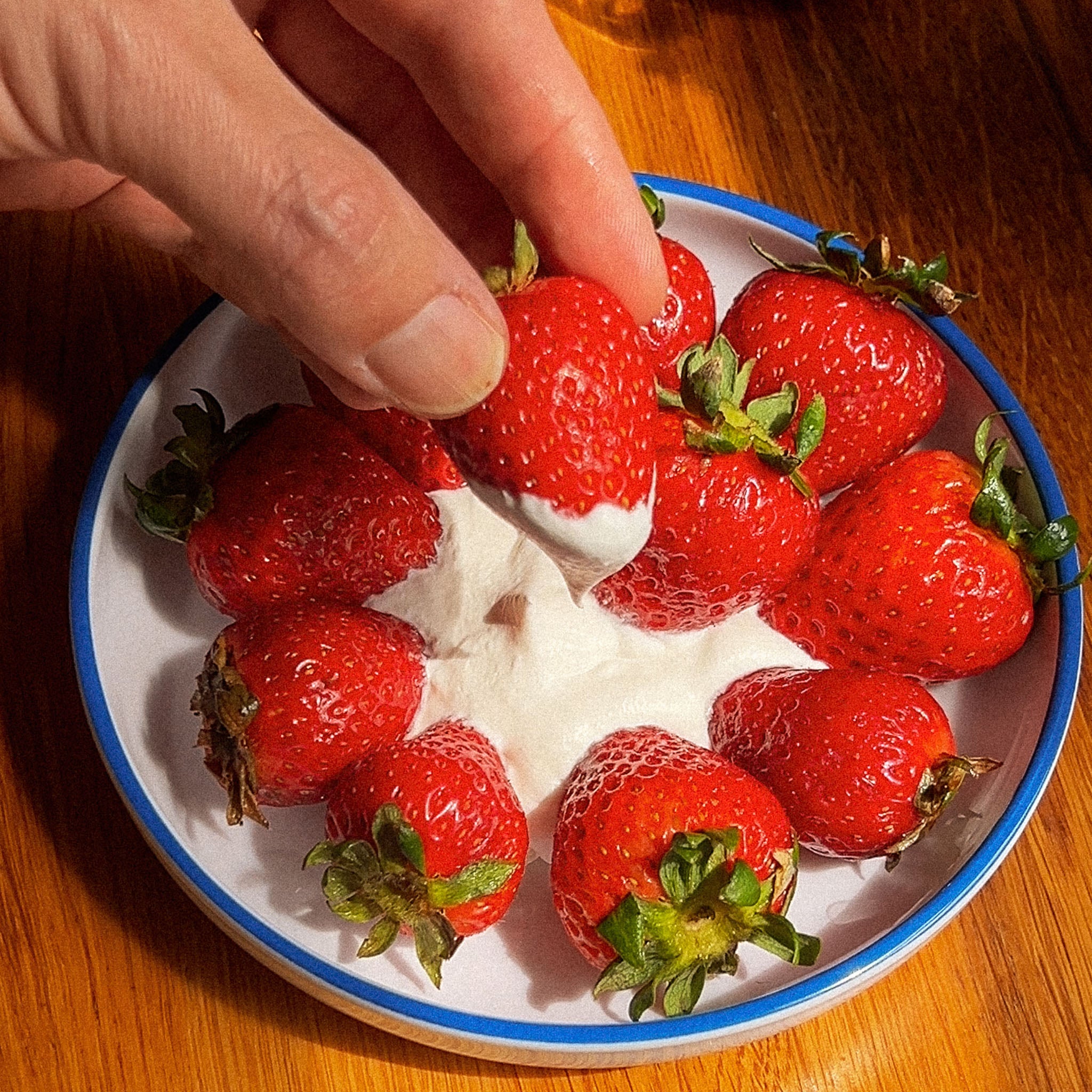 Strawberries being dipped into cool whip.